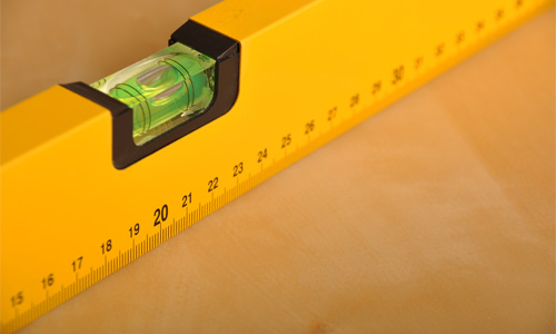 A yellow construction level with a green sight glass with an air bubble in it.