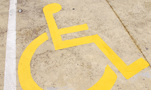 Handicapped parking space icon painted in yellow on concrete.