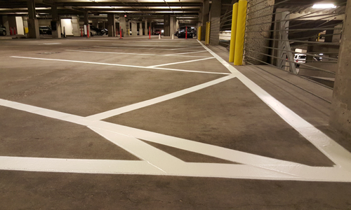White parking lot lines painted lines on a concrete parking garage floor.