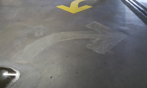 Concrete garage floor with painted yellow arrow.
