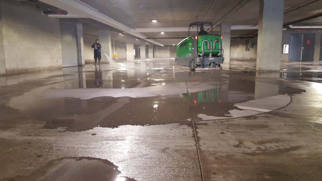 green parking garage sweeper cleaning a parking garage