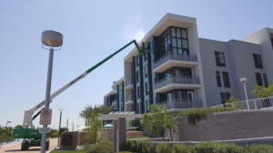 green and white boom lift beside a building with spray in the air